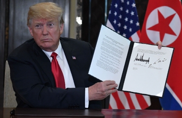 도널드 트럼프 미국 대통령과 김정은 북한 국무위원장이 대화를 계속 잇기로 약속하는 합의문에 서명하고 트럼프 대통령이 합의문을 들고 있는 모습.ⓒ스트레이트타임즈