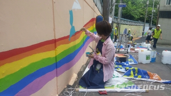 인근 초등학교 통학길을 발게 하기 위해 열심히 그림을 그리고 있는 회원들(사진 / 임희경 기자)
