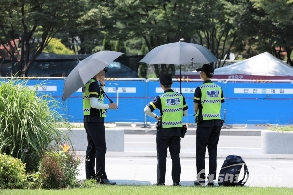 폭염 피해 우산 쓰고 근무하는 경찰들 [사진 / 오훈 기자]