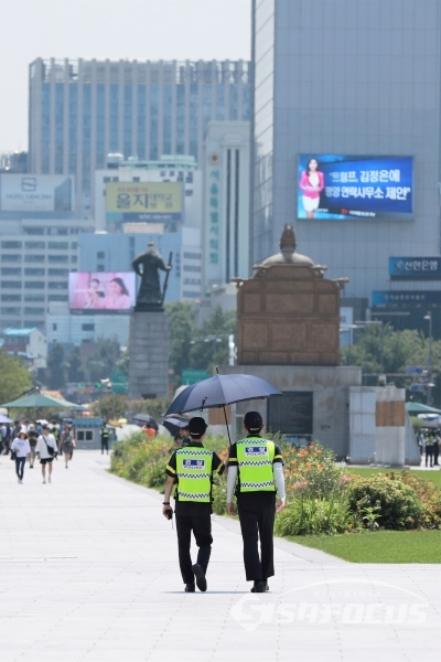 폭염 피해 우산 쓰고 근무하는 경찰들 [사진 / 오훈 기자]