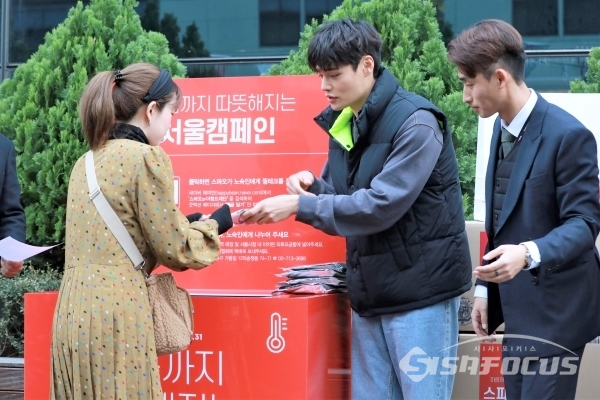 모델 정혁이 23일 열린 ‘웜테크 서울캠페인 전달식’에서 헌 옷을 기부한 시민에게 웜테크를 전달하고 있다. [사진 / 오훈 기자]