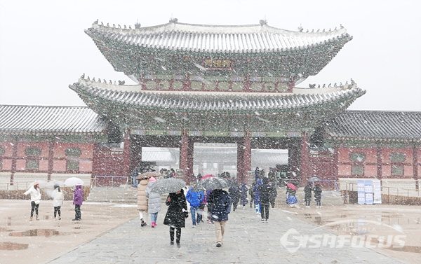 고궁의 눈내리는 풍경과 우산을 쓰고도 즐기는 관광객들 모습.     사진/강종민 기자