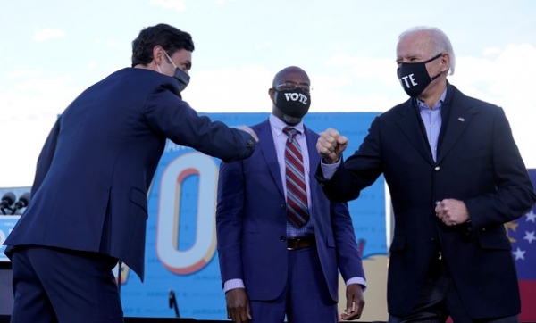 조 바이든 미국 대통령 당선인이 4일(현지시간) 조지아 연방 상원의원 민주당 후보인 래피얼 워녹(왼쪽) 및 존 오소프(가운데)와 무대에서 팔꿈치 인사를 나누고 있다. 사진 / ⓒ뉴시스