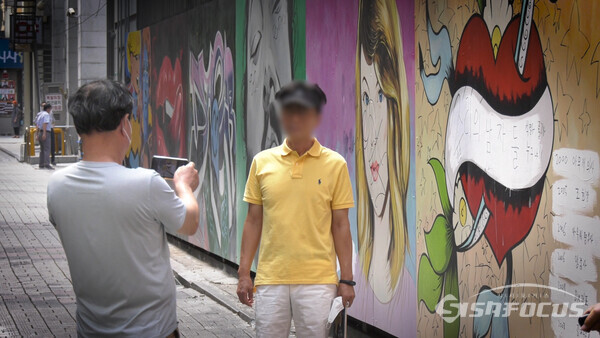윤석열 차기 대선 예비후보의 배우자를 비방하는 벽화가 그려진 장소에서 일부 사람들이 기념촬영을 하는 모습이 포착됐다. 사진 / 공민식 기자