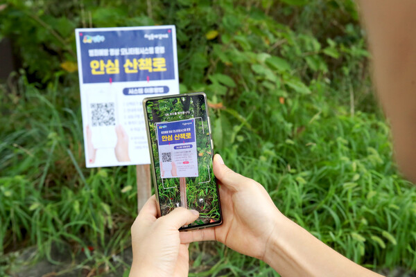 서울 성동구가 산지형 공원 산책로를 대상으로 전국 최초로 ‘산책로 범죄예방시스템’을 시범 운영한다. 공원 입구에 비치된 QR코드를 스캔하여 순서대로 누르면 성동구청의 통합운영센터와 연계되어 언제든지 긴급 도움을 받을 수 있다.  (성동구청 제공)