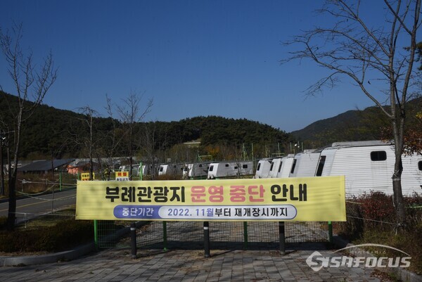 09일 부례관광단지 운영중단 현수막 뒤에는 한 대에 3100만원에 구입해 400만원에 판매하기로 결정한 캬라반 10대가 서 있다.사진/김진성 기자
