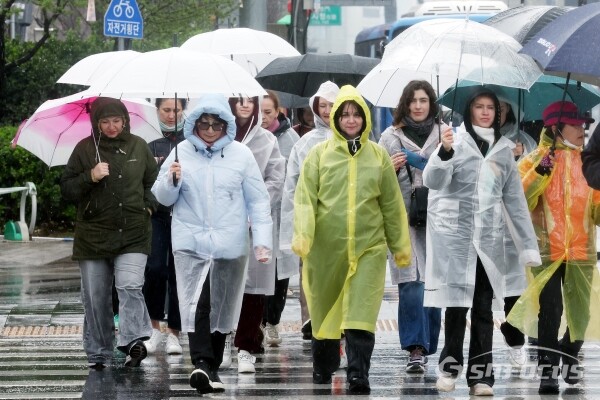 5일 우산과 우비를 쓴 외국인들이 이동하고 있다.(3)