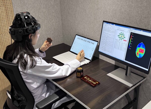 롯데웰푸드는 대한인공학회 학술대회에서 초콜릿 섭취가 스트레스 완화 등 정적 순기능을 확인했다고 발표했다. 사진은 뇌파 측정 장치를 착용하고 초콜릿을 섭취하는 연구 관계자 ⓒ롯데웰푸드